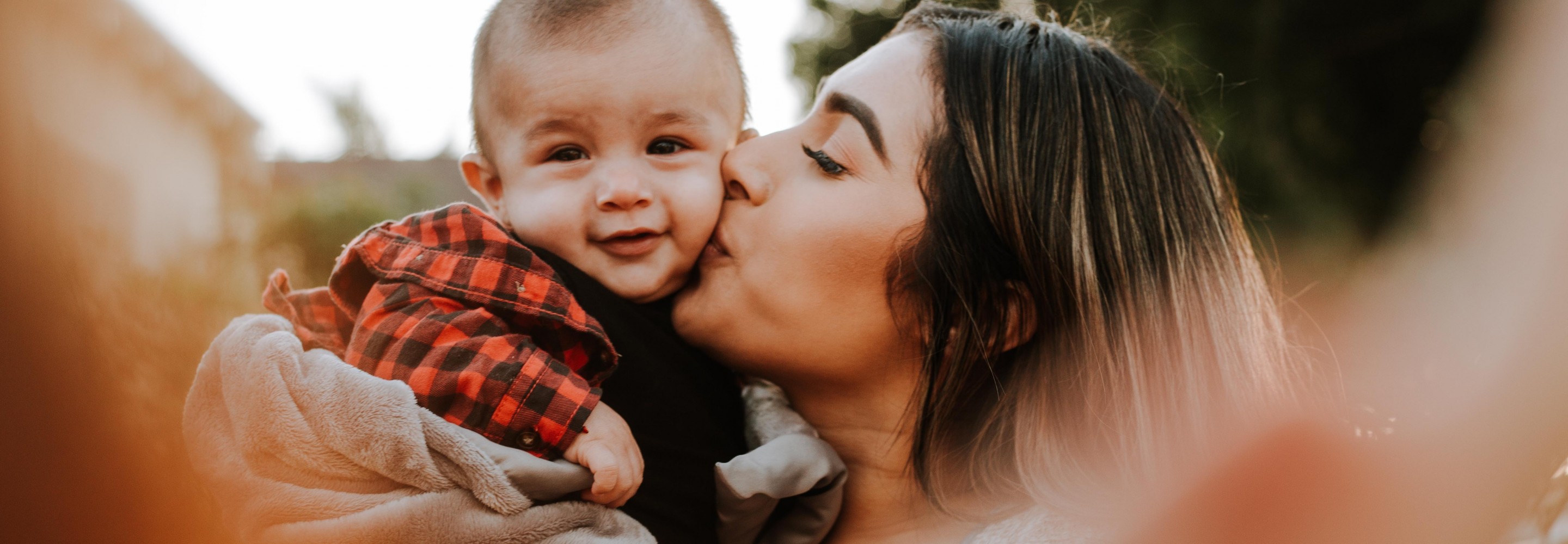 Woman kissing a smiling baby on the cheek; Photo by Omar Lopez on Unsplash