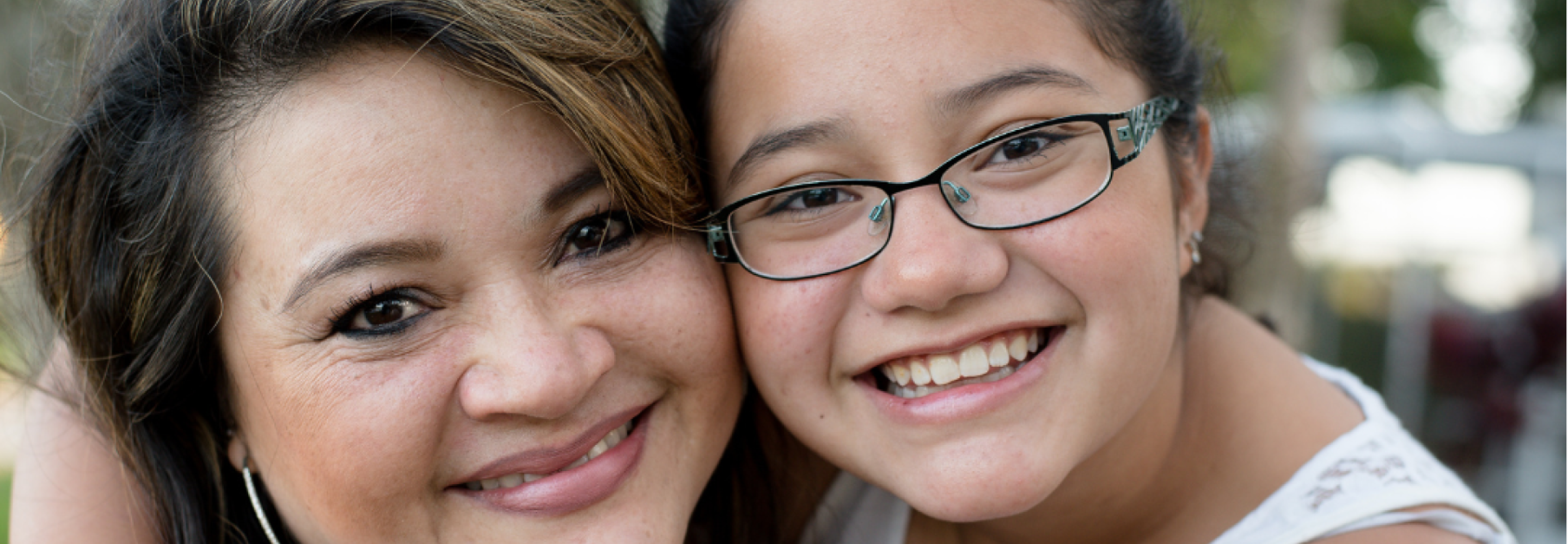 A mother hugs her child and they both smile at the camera