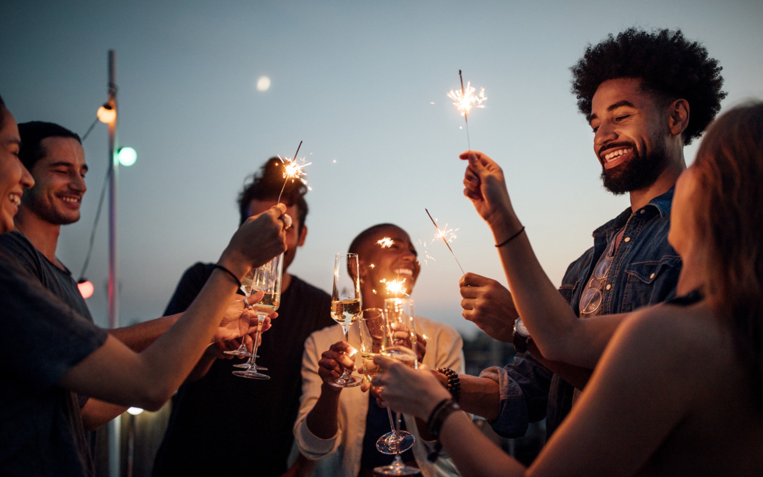 A group of young people light sparklers and toast champagne