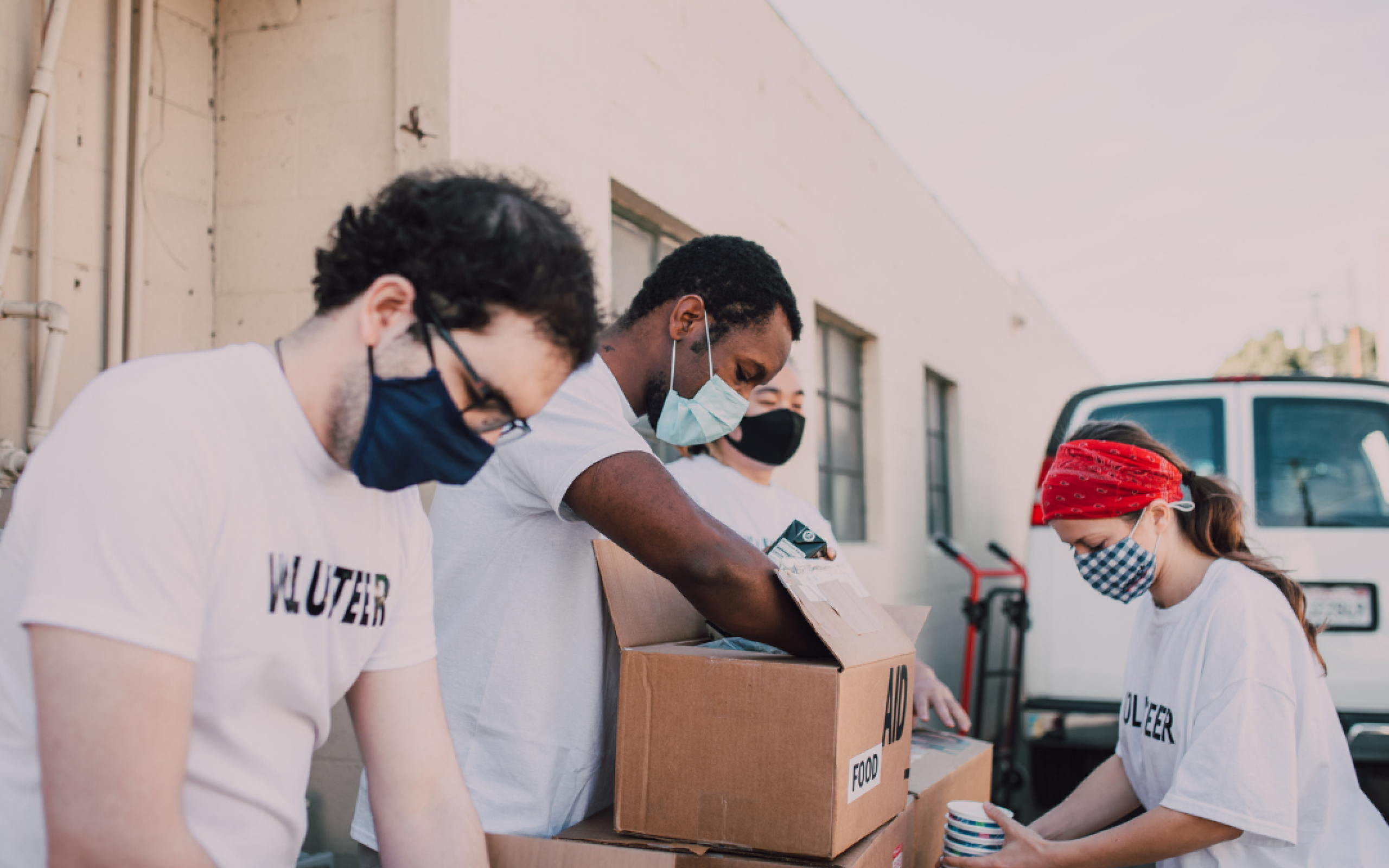 Four people in masks pack up food into boxes