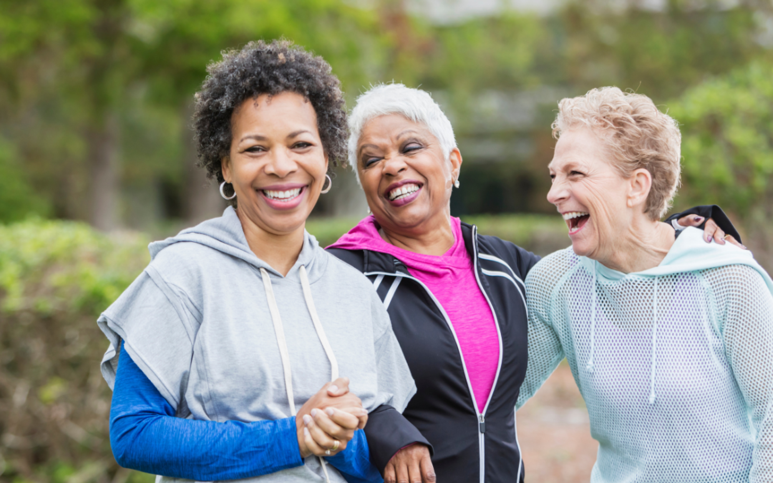 Three older women smile and laugh together