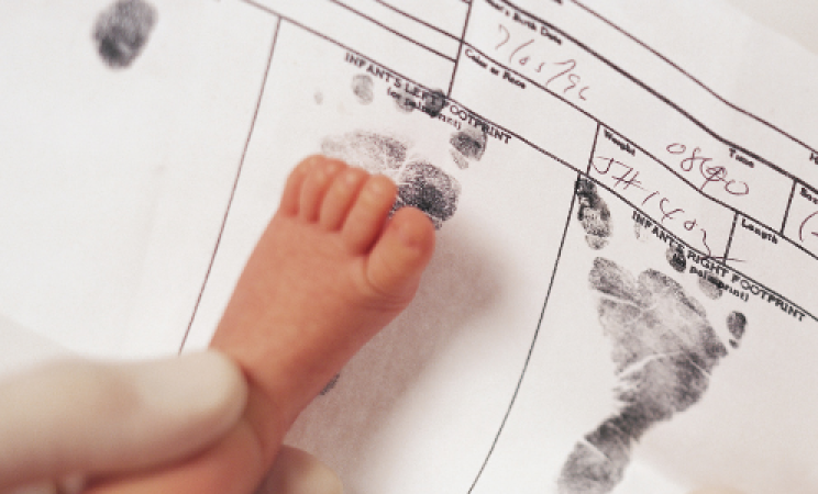 A birth certificate is being stamped with a baby's footprint