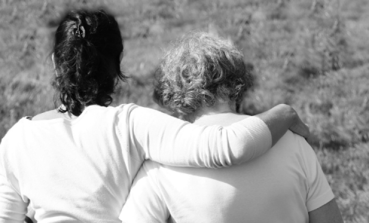 A mother and daughter walk together, the daughter has her arm around her mother's shoulders.