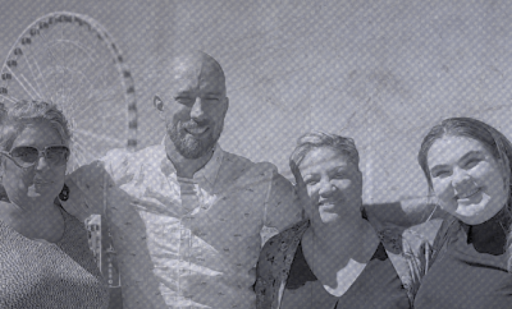 Four staff members pose  in front a ferris wheel