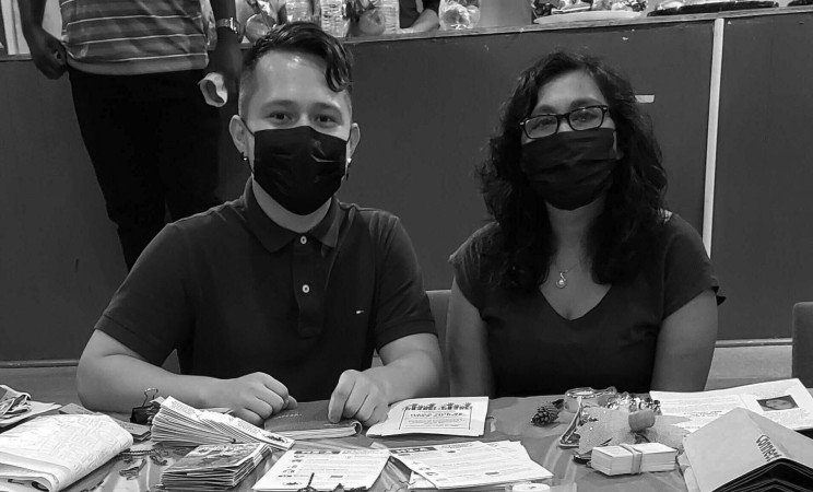 Jordy and Alejandra pose at an outreach table with the PFP