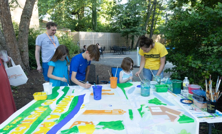 Several children help paint the Walls for Justice mural at our Jubilee for Justice