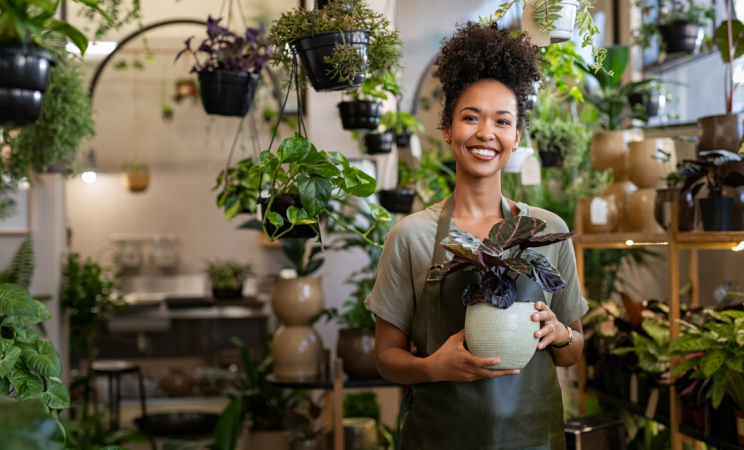 A woman who owns a plant store poses for a photo holding a plant