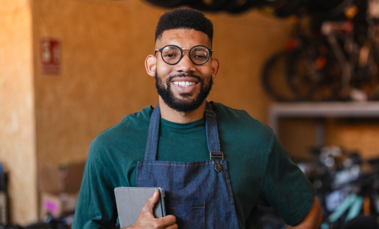 A man in an apron holds a computer