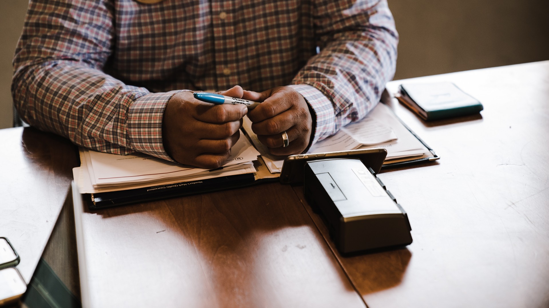 Person sitting in front of table holding blue marker