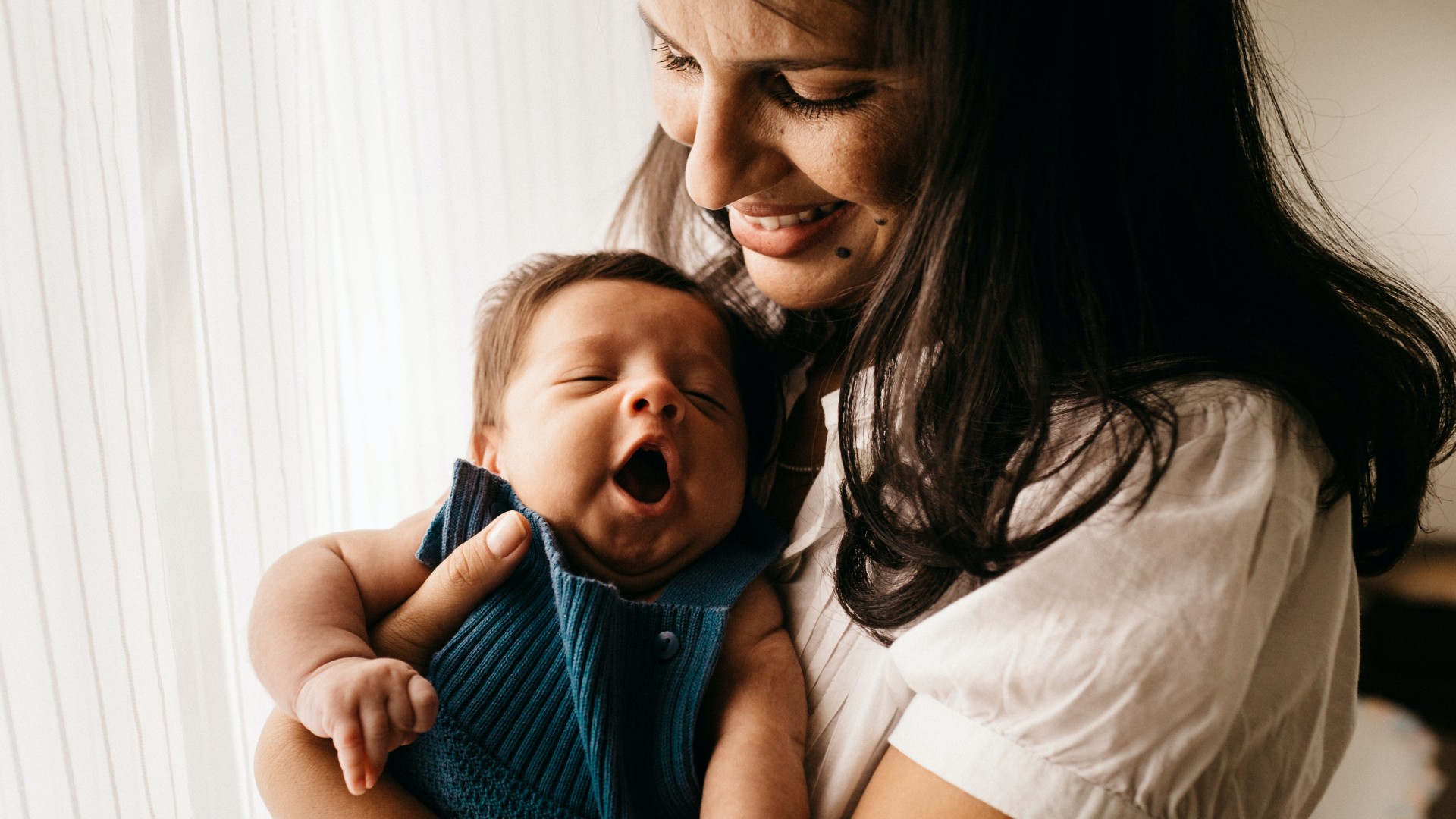 Young woman-presenting person holding an infant