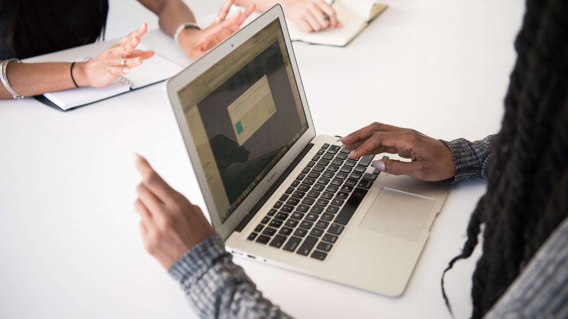Woman typing at a computer with a team; Photo by Christina @ wocintechchat.com on Unsplash