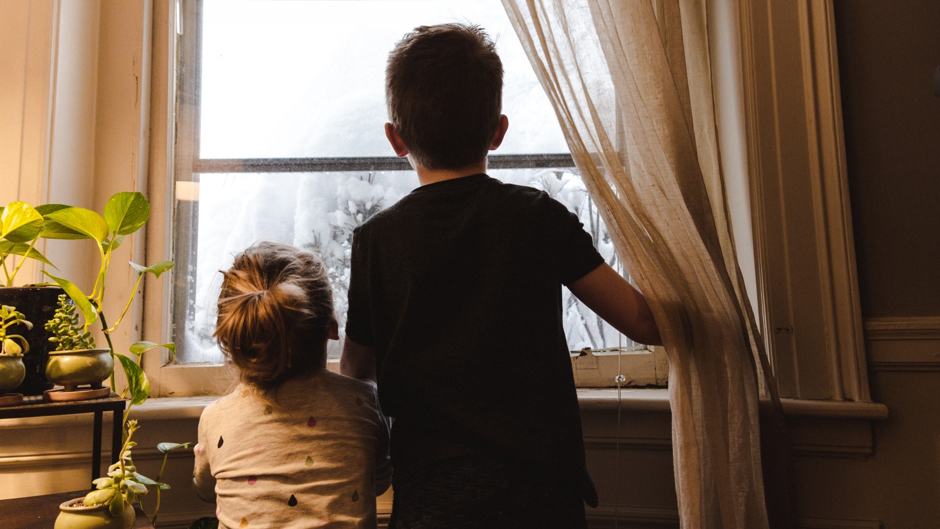 Two children looking out a window; Photo by Kelly Sikkema on Unsplash