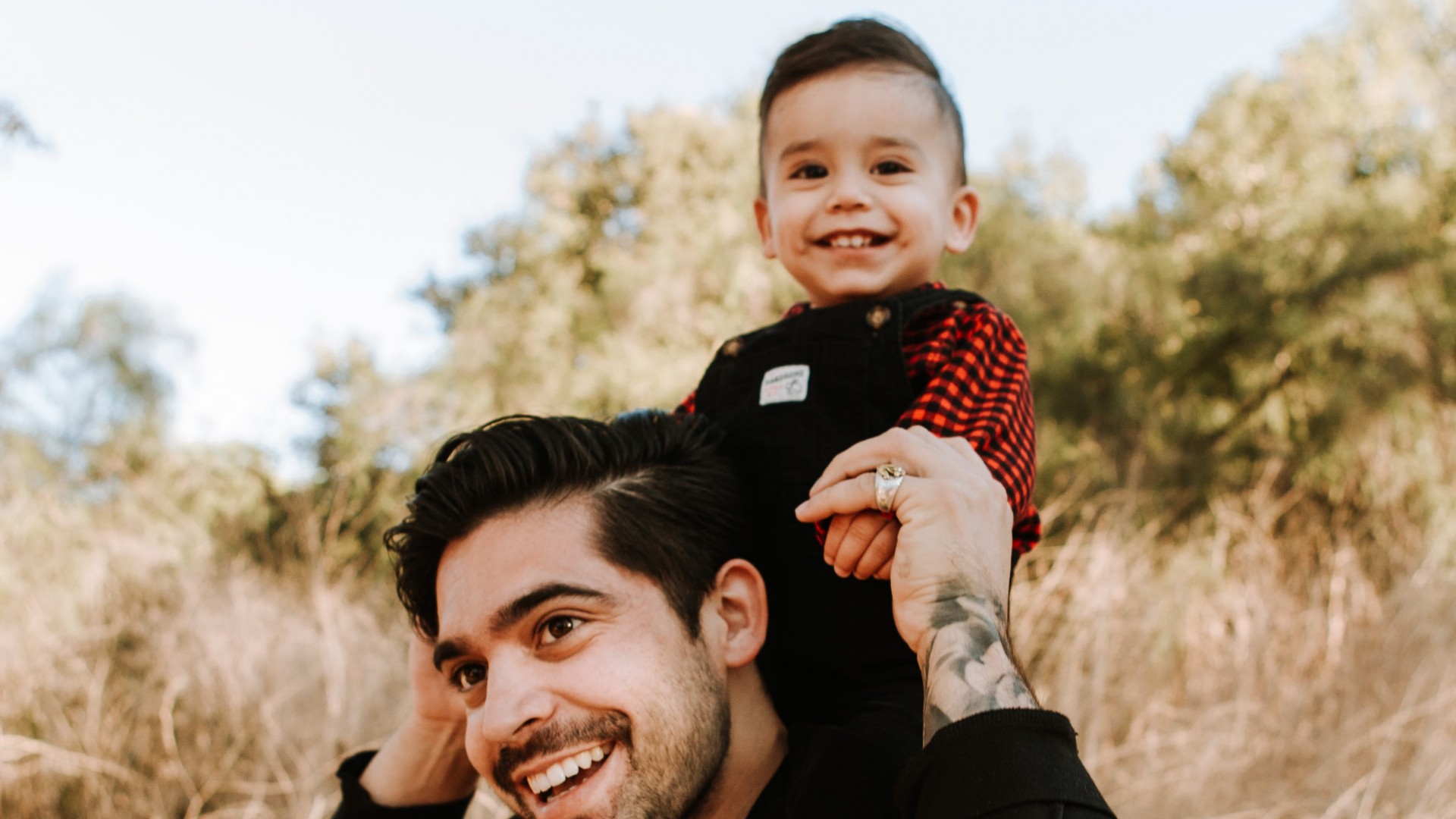 Smiling father carrying his son on his back in a park, Photo by Omar Lopez on Unsplash