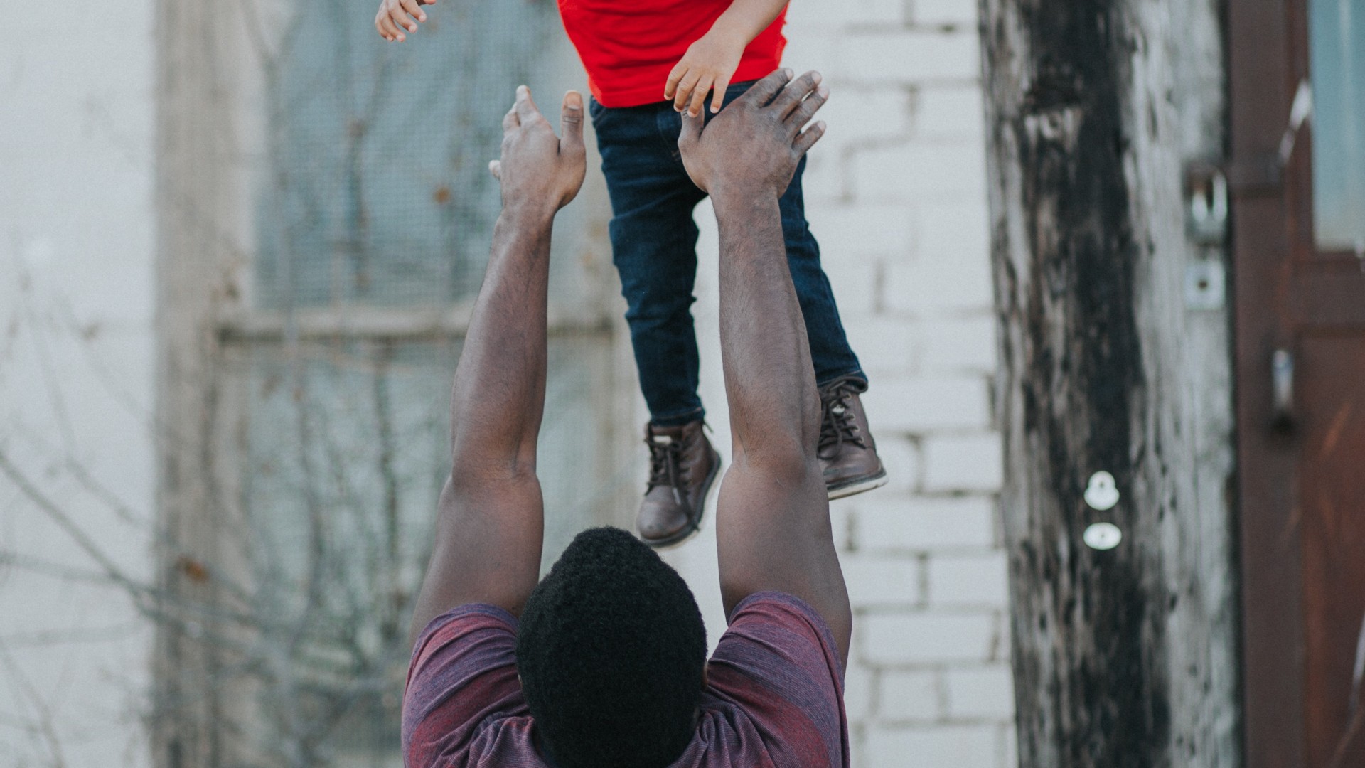 an adult man plays with his nephew by tossing him in the air 