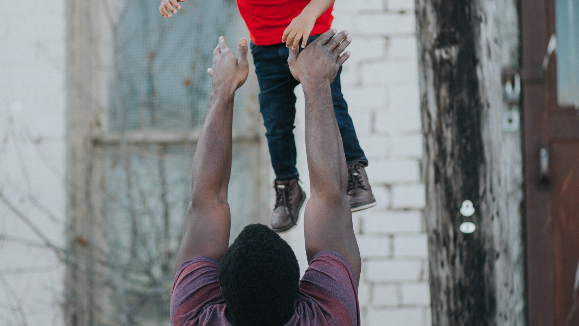 an adult man plays with his nephew by tossing him in the air