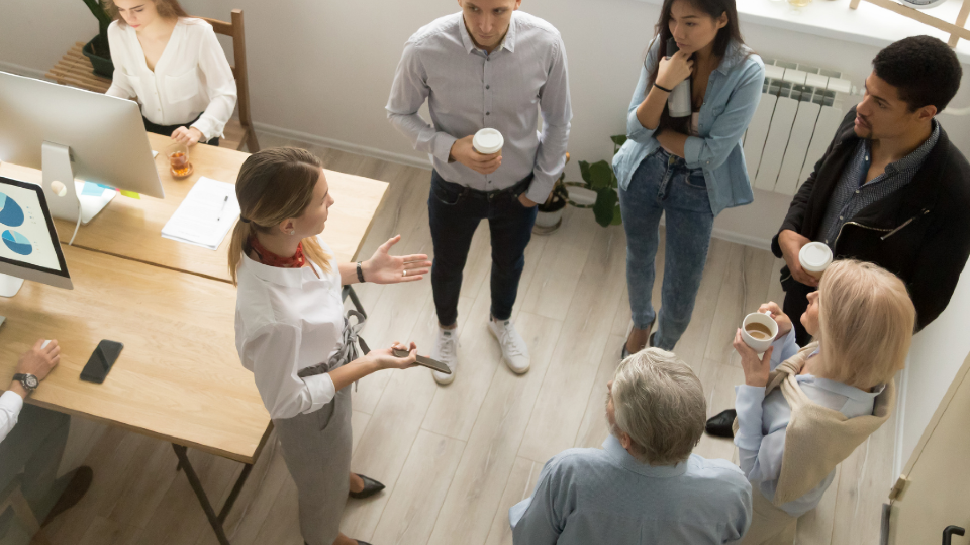 A group of young professionals stands in a circle chatting