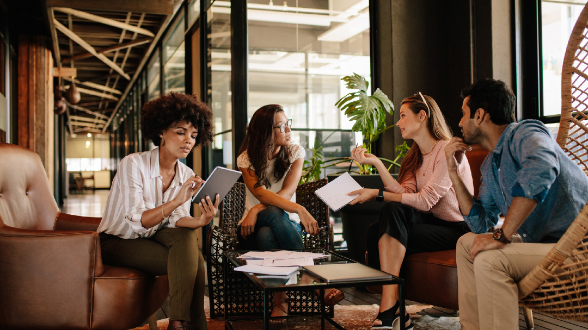 Four young professionals sit around a coffee table chatting