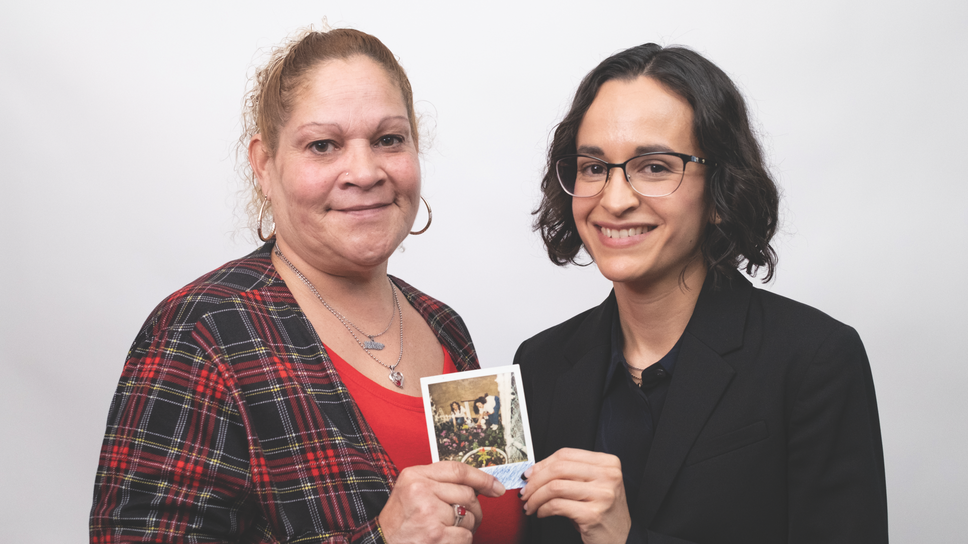 Attorney Andria Bibiloni poses with client Melinda, they both are holding onto a photo of Melinda's beloved side yard