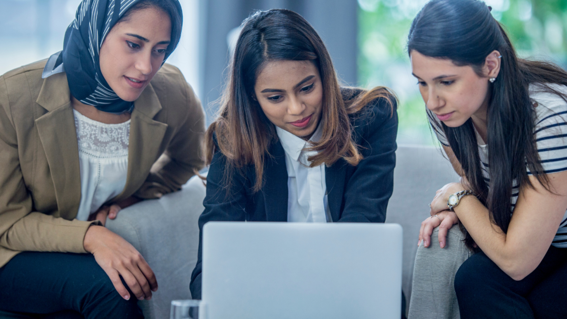 Three women look at a laptop