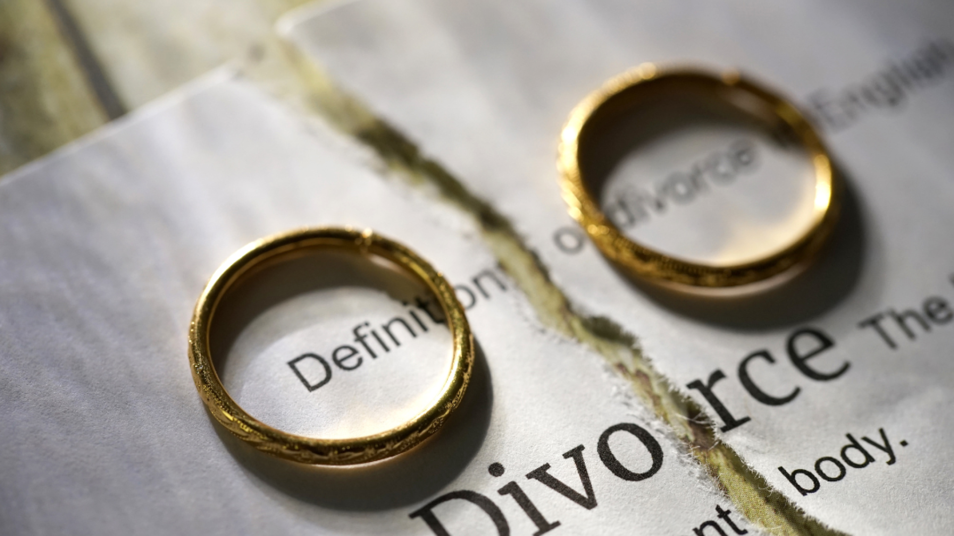 Two wedding rings sit atop a piece of paper that reads "Divorce"
