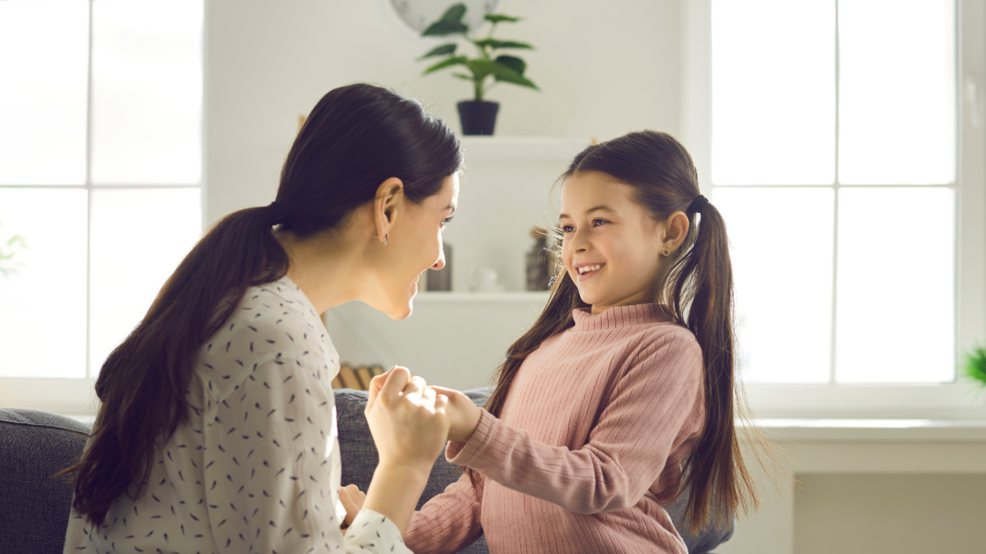 A woman and child play together in their living room on the couch