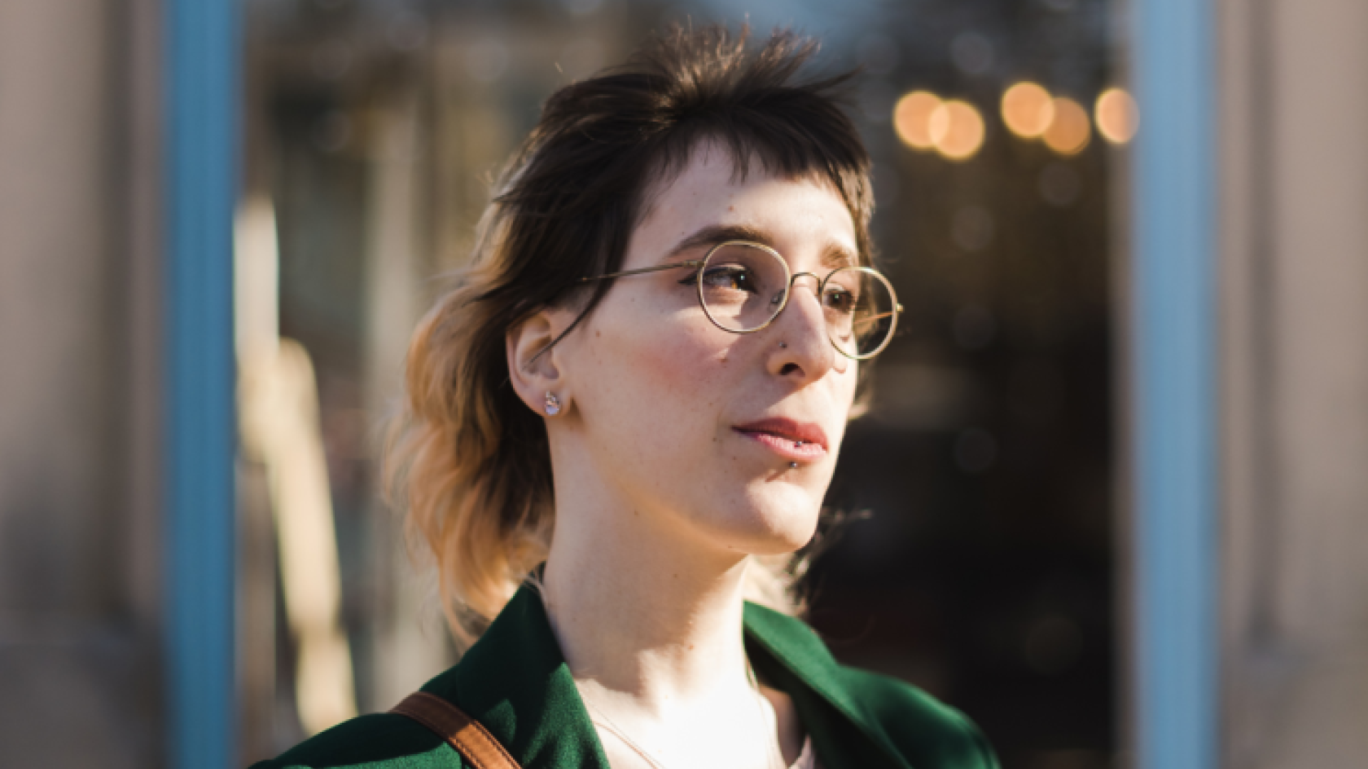 A woman's portrait. She has glasses and a ponytail. 