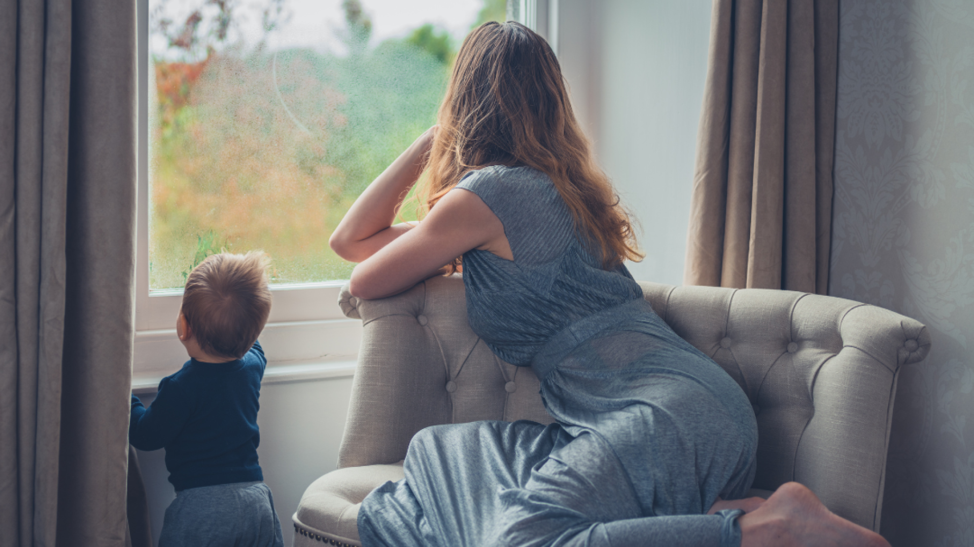 a woman and her toddler look out a window