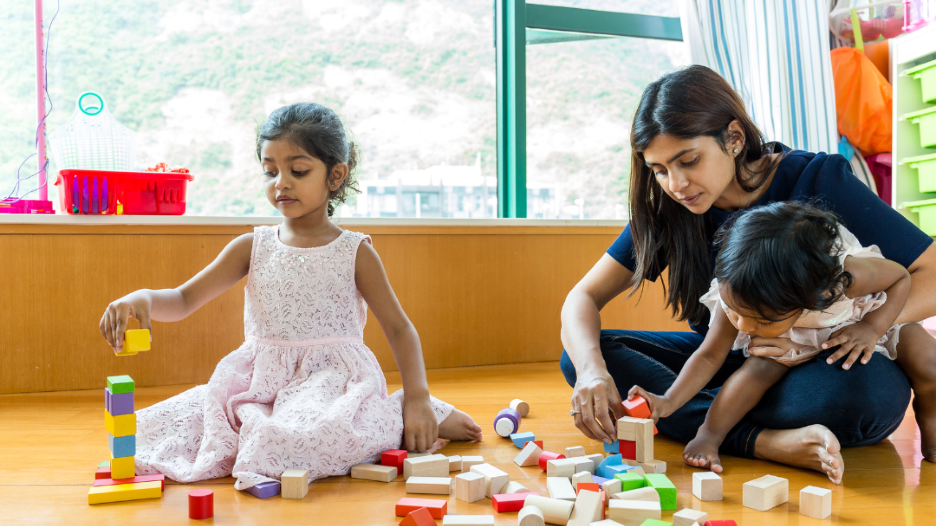 A mother and her two children play with building blocks