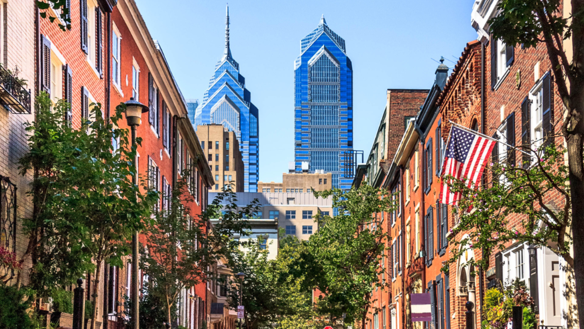 the skyline of philadelphia as seen through a street of rowhomes