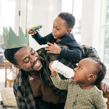 A father plays with his two toddlers. 